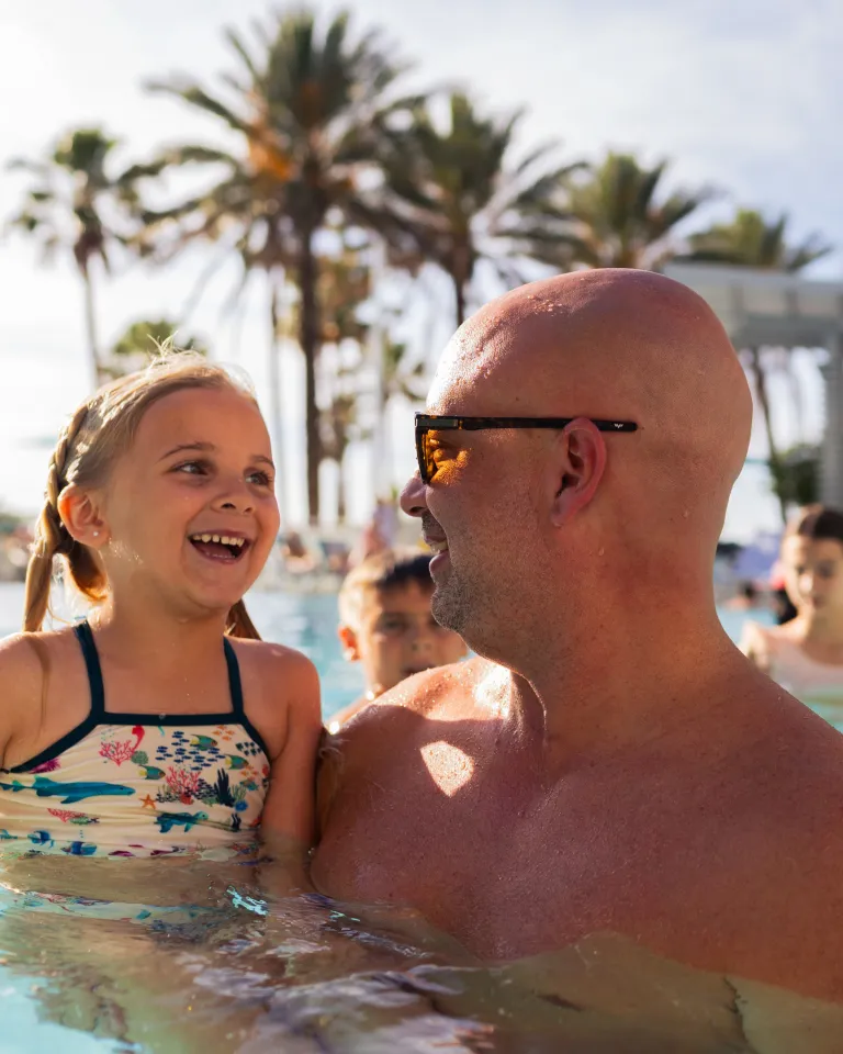 A man and daughter playing in a resort pool