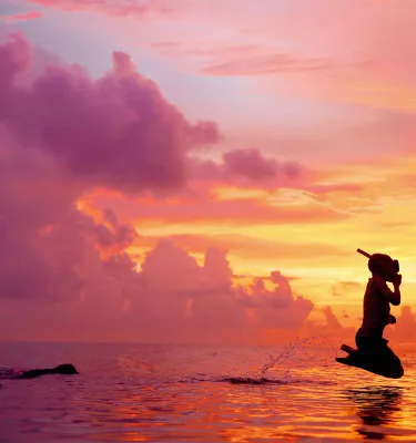 Mergulhador de snorkel pulando no Golfo do México durante um lindo pôr do sol na Honeymoon Island.