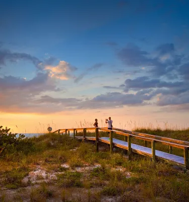 Um casal tirando fotos durante o pôr do sol em uma passarela na bela Pass-a-Grille Beach perto de St. Pete Beach, Flórida