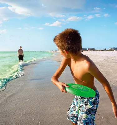 Un niño jugando frisbee con su papá en la playa en Treasure Island cerca de St. Pete Beach