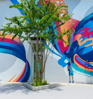A mural with brightly colored swirls named "Make Believe" by Tes One on Main Street in Dunedin