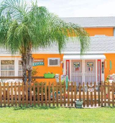 Ein knalliges orangefarbenes Haus in Gulfport mit einem Lattenzaun und Schildern zum Fischen an der Tür
