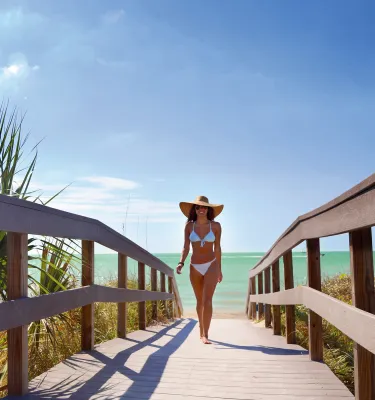 A young lady dressed in bikini walking Indian Rocks Beach boardwalk.