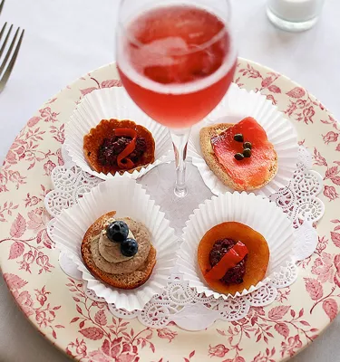 French canapes and a glass of red wine sit on top of a pink flowered plate at Cafe Largo in Largo, FL