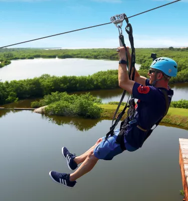 ein Mann fährt Seilrutsche über dem Mobbly Bayou Wilderness Preserve in Oldsmar; Unter ihm sind ein See und Bäume zu sehen