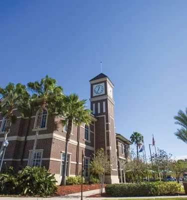 Pinellas Park train station exterior brick walls showing the clock at the top of the tower, blue skies and palm trees.