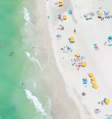 Vista aérea de cabanas de praia amarelas e águas verde-esmeralda da Ilha do Tesouro.