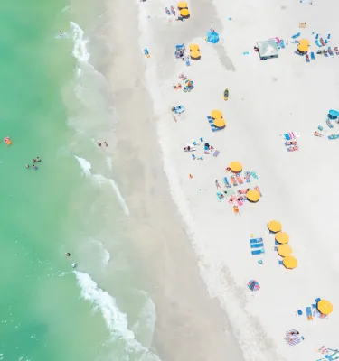 Aerial view of yellow beach cabanas and emerald-green waters of Treasure Island.