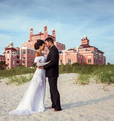 A couple hugging each other posing in front of Don Cesar for their wedding.