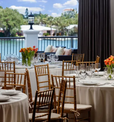 An indoor wedding reception room decorated with orange flowers with a view for the water.