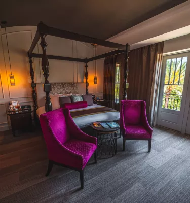 Magenta chairs and antique looking bedroom with french doors at The Birchwood boutique hotel