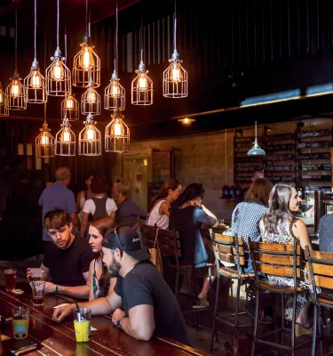 Several people enjoying drinks a an indoor bar at Three Daughters Brewing.