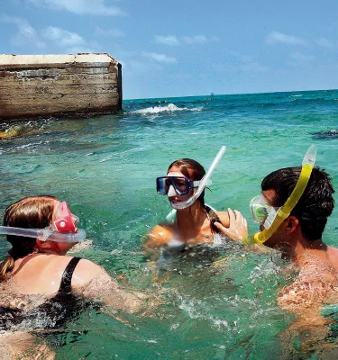 A group snorkeling in clear blue green water next to a fort.