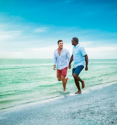 Two gay men walk hand-in-hand at the surf's edge on Clearwater Beach