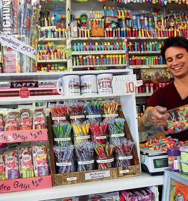 A young man surrounded by lots of candy on display at Candy Kitchen store.