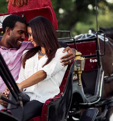 An African-American couple looking closely to each other while riding a carriage.