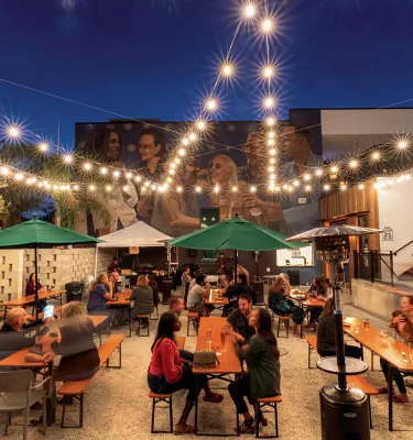 Several people enjoying drinks in the outdoor area of Grand Central Brew House at dusk.