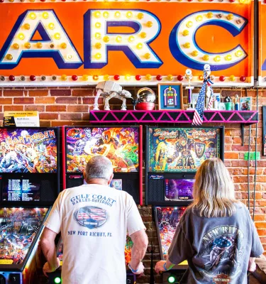 Two people play pin ball at the Replay Museum
