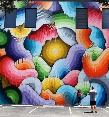 A couple taking a photo in front of the Space Rainbows mural