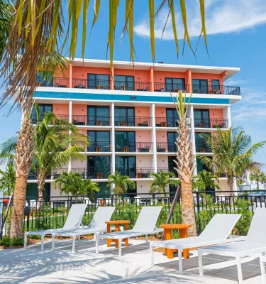 Eine Außenaufnahme des Hilton Garden Inn Hotel in St. Pete Beach mit markanten rosa und grünen Elementen.