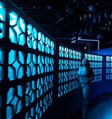 a young woman explores one of the exhibits at Fairgrounds St. Pete, standing in blue light next to a decorative wall