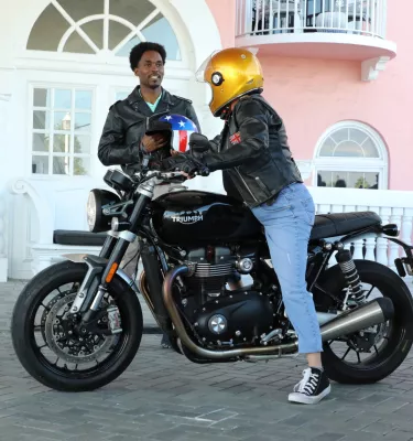 Man and motorcyclist talking outside the front doors of the lobby to the pink Don CeSar hotel on St. Pete beach. 
