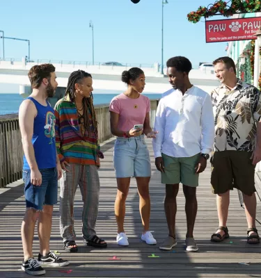 Five cast members filming season 2 of Life's Rewards stand of the boardwalk at John's Pass during a sunny Florida day.