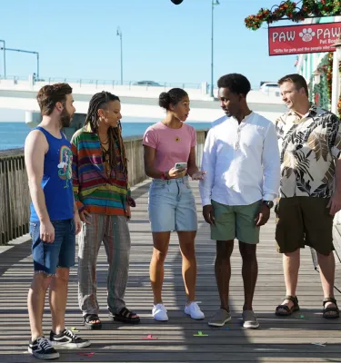 Five cast members filming season 2 of Life's Rewards stand of the boardwalk at John's Pass during a sunny Florida day.