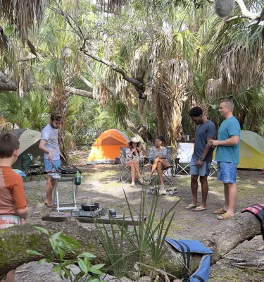 Behind the scenes of the cast and crew of Life's Rewards filming a camping scene in Fort De Soto Park, featuring tents, food and lifejackets.
