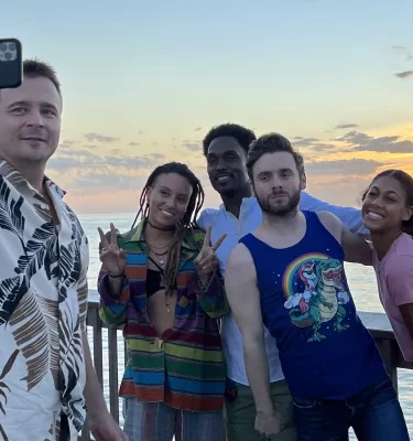 Five cast members of the series Life's Rewards pose for a selfie with the pink and yellow sunset at Pier 60 in Clearwater Beach.