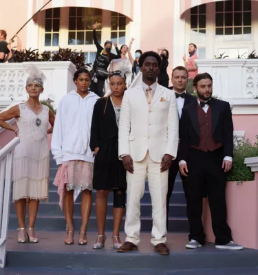 Television crew and cast members looking off into the distance on the steps of the pink Don CeSar hotel on St. Pete Beach. 