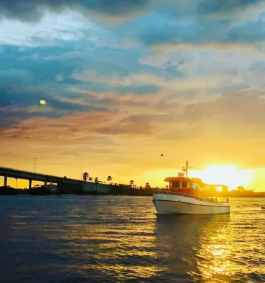 Little Toot Dolphin Adventure tour in Clearwater Beach featuring a boat on the water during sunset.
