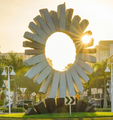 The sun rises behind a stone sun sculpture in Saint Pete's Edge District.