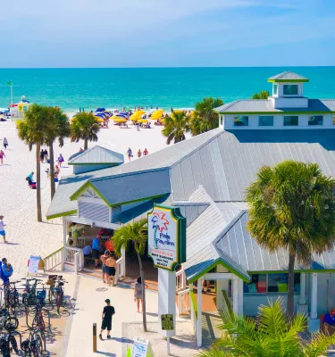 Do lado de fora do restaurante Crabby's Beachside Pavilion de Clearwater Beach, com pessoas caminhando ao redor, observando a água azul do oceano.