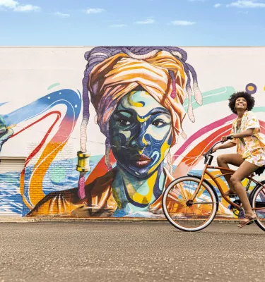 Woman on a bicycle infront of a mural