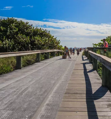 a wooden walkway with a mat surface runs to the sand, with vegetation on either side at Upham Beach