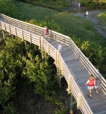 People stroll along a wooden boardwalk in Boca Ciega Millennium Park