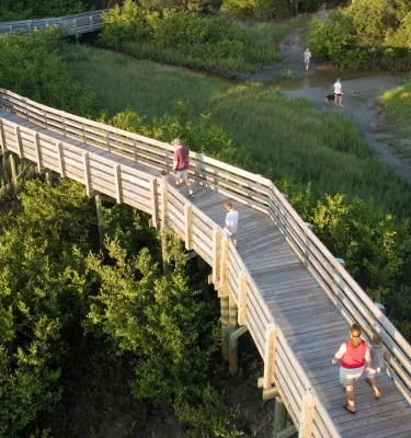 A wooden boardwalk with a few people walking through Boca Ciega Millennium Park