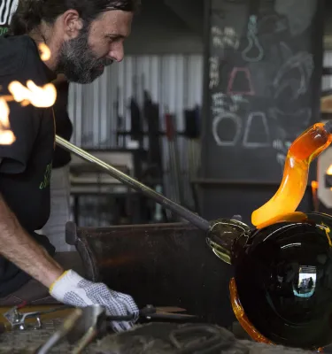 A man works with molten glass at the DMG School Project