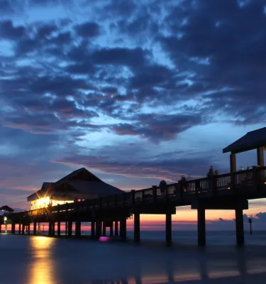 deep blue and purple sunset with clouds over Pier 60 which is illuminated by lights underneath