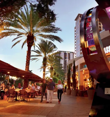 A family walks past diners at outdoor tables at Cassis in downtown St. Pete at dusk, 