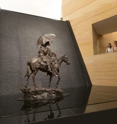Two people peer at the waterfall and sculpture in the James Museum lobby.