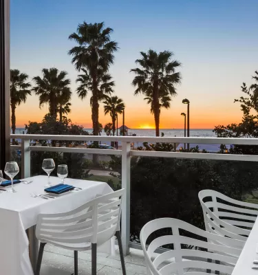 white chairs and a table with a white table cloth at Ocean Hai restaurant overlook sunset at the beach