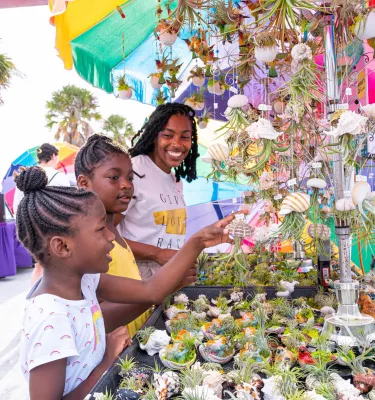A mom and her two daughters look at decorated seashells and other souvenirs at the Pier 60 sunset celebration in Clearwater Beach