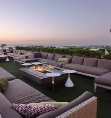 Birchwood Canopy bar & lounge outside during twilight on the water in St. Pete featuring couches and a fireplace.