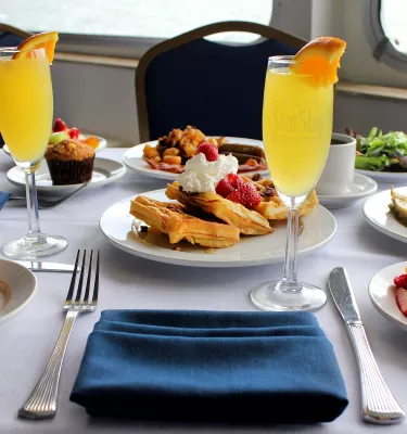 Photo of a cruise brunch set up featuring two mimosas, waffles, strawberries, toast and more.