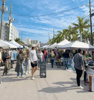 A crowd of people walking outside at the Mezzo Market in downtown St. Pete, FL.