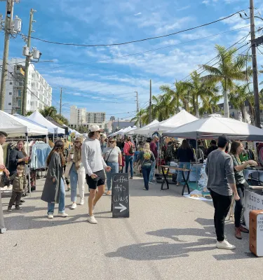A crowd of people walking outside at the Mezzo Market in downtown St. Pete, FL.