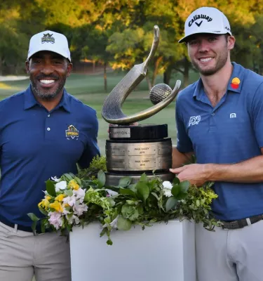 Two golfers holding a trophy at the PGA Valspar Championship.