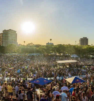 Skyline image of downtown St. Pete with a crowd of people attending the Reggae Rise Up Festival at Vinoy Park.